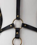 Black leather harness with gold rings on a mannequin against a white background