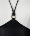 Black leather strap of the corset by bijou by juju with a brass clasp on a white background