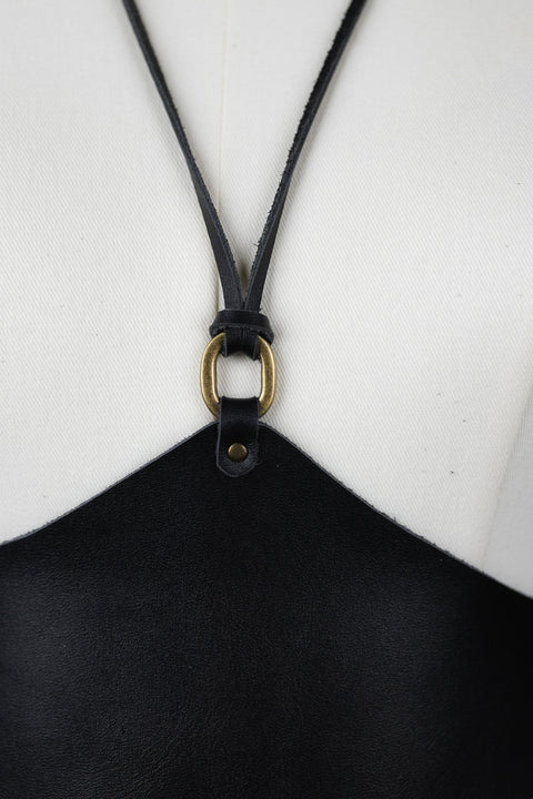 Black leather strap of the corset by bijou by juju with a brass clasp on a white background